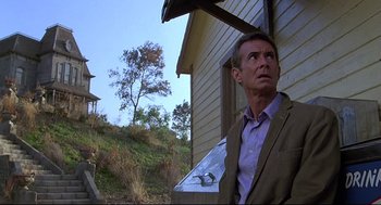 Movie still from “Psycho III” (1986), directed by Anthony Perkins – A man standing outside of a house looking up at the sky; Medium shot, Low angle