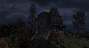 Movie still from “Psycho III” (1986), directed by Anthony Perkins – A man standing on the steps leading up to a house; Extreme Wide shot, Low angle
