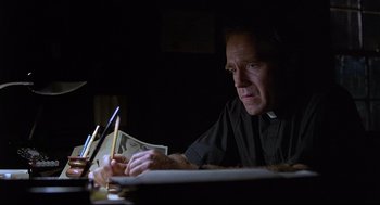 Movie still from “Psycho III” (1986), directed by Anthony Perkins – A man sitting at a table writing on a piece of paper; Close Up shot, Low angle