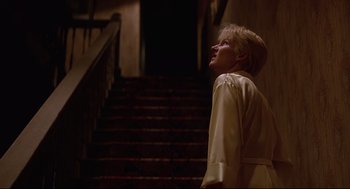 Movie still from “Psycho III” (1986), directed by Anthony Perkins – A woman standing on the stairs looking up; Medium shot, Low angle