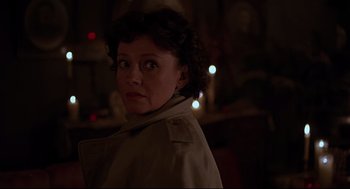 Movie still from “Psycho III” (1986), directed by Anthony Perkins – A woman in a trench coat is looking at the camera; Close Up shot, Over the shoulder angle