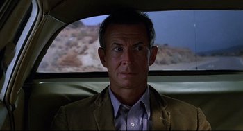 Movie still from “Psycho III” (1986), directed by Anthony Perkins – A man sitting in the back seat of a car; Close Up shot, Low angle