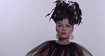 Movie still from “Puzzle of a Downfall Child” (1970), directed by Jerry Schatzberg – A woman in a black dress with feathers on her head; Close Up shot, Low angle