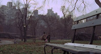 Movie still from “Puzzle of a Downfall Child” (1970), directed by Jerry Schatzberg – Two people are walking in a park near a park bench; Extreme Wide shot, High angle