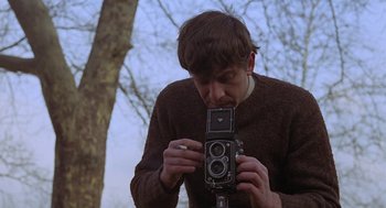Movie still from “Puzzle of a Downfall Child” (1970), directed by Jerry Schatzberg – A man holding an old camera in front of a tree; Close Up shot, Low angle