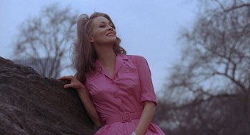 Movie still from “Puzzle of a Downfall Child” (1970), directed by Jerry Schatzberg – A woman in a pink dress leaning on a rock; Medium shot, Low angle
