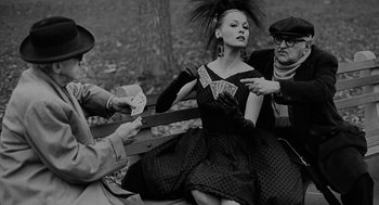 Movie still from “Puzzle of a Downfall Child” (1970), directed by Jerry Schatzberg – A woman sitting on top of a wooden bench next to two men; Medium shot, Over the shoulder angle