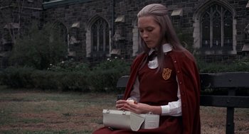 Movie still from “Puzzle of a Downfall Child” (1970), directed by Jerry Schatzberg – A woman sitting on the ground holding a white purse; Medium shot, High angle