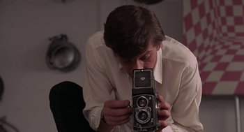 Movie still from “Puzzle of a Downfall Child” (1970), directed by Jerry Schatzberg – A young man holding an old camera in his hands; Close Up shot, Low angle