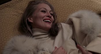 Movie still from “Puzzle of a Downfall Child” (1970), directed by Jerry Schatzberg – A woman smiling while wearing a white sweater and a fur coat; Close Up shot, Overhead angle