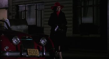 Movie still from “Puzzle of a Downfall Child” (1970), directed by Jerry Schatzberg – A woman wearing a red hat and a black coat walking down the street; Wide shot, Over the shoulder angle
