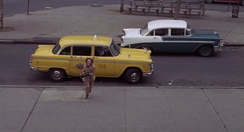 Movie still from “Puzzle of a Downfall Child” (1970), directed by Jerry Schatzberg – A woman standing on the side of the road next to a taxi cab; Wide shot, High angle
