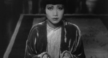 Movie still from “Puzzle of a Downfall Child” (1970), directed by Jerry Schatzberg – An old black and white photo of a young woman; Medium shot, High angle