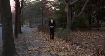 Movie still from “Puzzle of a Downfall Child” (1970), directed by Jerry Schatzberg – A man in a black suit standing on the side of a road; Wide shot, Low angle