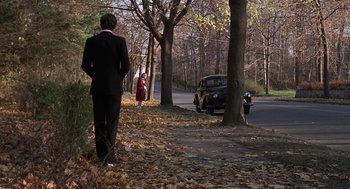 Movie still from “Puzzle of a Downfall Child” (1970), directed by Jerry Schatzberg – A man in a suit standing next to a car on the side of the road; Wide shot, Over the shoulder angle