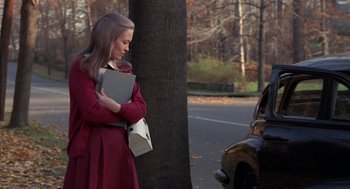 Movie still from “Puzzle of a Downfall Child” (1970), directed by Jerry Schatzberg – A woman in a red coat is standing next to a tree; Medium shot, High angle