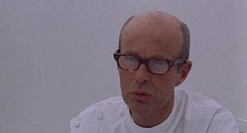 Movie still from “Puzzle of a Downfall Child” (1970), directed by Jerry Schatzberg – A bald man wearing glasses and a white shirt; Close Up shot, Low angle