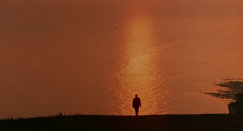 Movie still from “Quadrophenia” (1979), directed by Franc Roddam – A person standing in front of a body of water at sunset; Extreme Wide shot, Low angle