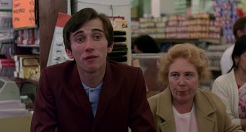 Movie still from “Quadrophenia” (1979), directed by Franc Roddam – A man and a woman sitting next to each other in a store; Medium shot, Over the shoulder angle