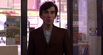 Movie still from “Quadrophenia” (1979), directed by Franc Roddam – A young man in a brown jacket standing in front of a building; Medium shot, Low angle