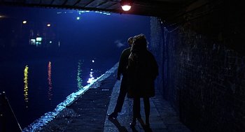 Movie still from “Quadrophenia” (1979), directed by Franc Roddam – Two people standing on the side of a bridge at night; Wide shot, High angle