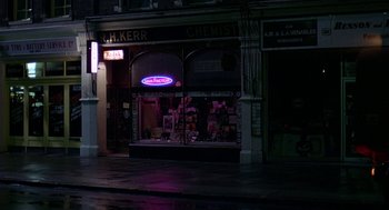 Movie still from “Quadrophenia” (1979), directed by Franc Roddam – A store front lit up at night on a rainy night; Wide shot, High angle