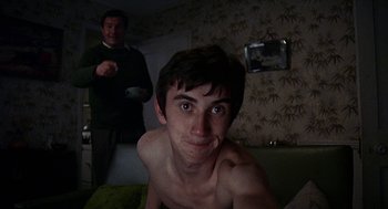 Movie still from “Quadrophenia” (1979), directed by Franc Roddam – A young man with a bowl in his hand and another man in the background; Medium shot, Low angle
