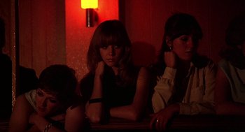 Movie still from “Quadrophenia” (1979), directed by Franc Roddam – A group of women sitting next to each other in front of a lamp; Medium shot, Low angle