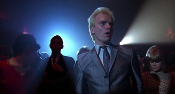 Movie still from “Quadrophenia” (1979), directed by Franc Roddam – A man in a suit and tie standing next to another man in a suit and tie; Close Up shot, Low angle