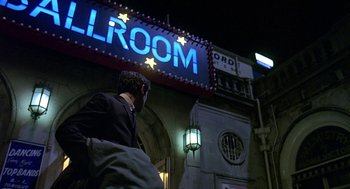 Movie still from “Quadrophenia” (1979), directed by Franc Roddam – A man walking in front of a movie theater at night; Wide shot, Low angle