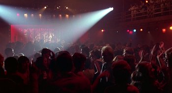 Movie still from “Quadrophenia” (1979), directed by Franc Roddam – A crowd of people in a room with a spotlight shining on them; Wide shot, High angle