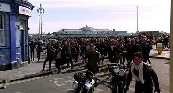 Movie still from “Quadrophenia” (1979), directed by Franc Roddam – A large group of people are marching down the street; Wide shot, High angle