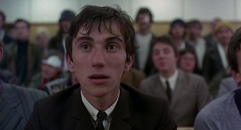 Movie still from “Quadrophenia” (1979), directed by Franc Roddam – A man in a suit and tie in front of a group of people; Close Up shot, High angle