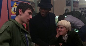 Movie still from “Quadrophenia” (1979), directed by Franc Roddam – A group of people standing next to each other in a room; Medium shot, Over the shoulder angle