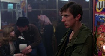 Movie still from “Quadrophenia” (1979), directed by Franc Roddam – A man in a green jacket is sitting in a room; Close Up shot, Over the shoulder angle