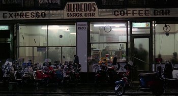 Movie still from “Quadrophenia” (1979), directed by Franc Roddam – A group of motorcycles parked in front of a restaurant; Extreme Wide shot, High angle