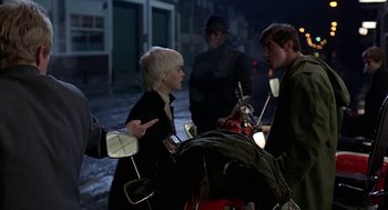 Movie still from “Quadrophenia” (1979), directed by Franc Roddam – A group of people standing next to each other on a street; Medium shot, Over the shoulder angle