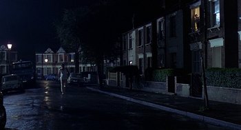 Movie still from “Quadrophenia” (1979), directed by Franc Roddam – A person walking down a street at night; Extreme Wide shot, Low angle