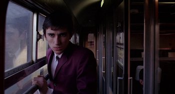 Movie still from “Quadrophenia” (1979), directed by Franc Roddam – A man in a suit and tie on a train; Medium shot, Low angle