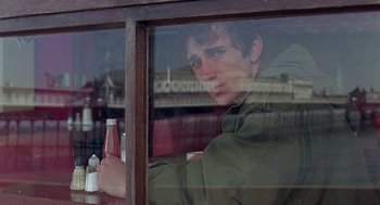 Movie still from “Quadrophenia” (1979), directed by Franc Roddam – A man sitting at a table with a bottle of beer; Close Up shot, Over the shoulder angle