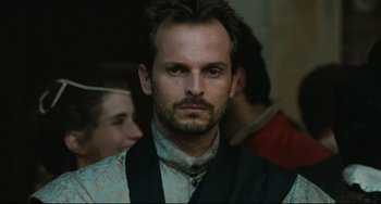 Movie still from “Queen Margot” (1994), directed by Patrice Chéreau – A person wearing a suit and tie; Close Up shot, Over the shoulder angle