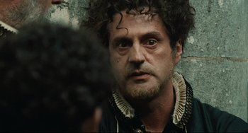 Movie still from “Queen Margot” (1994), directed by Patrice Chéreau – A person with a beard and curly hair; Close Up shot, Over the shoulder angle