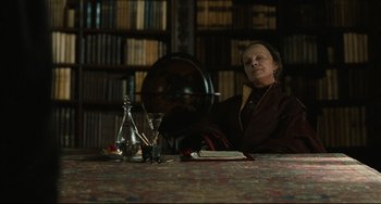 Movie still from “Queen Margot” (1994), directed by Patrice Chéreau – An older woman sitting at a table in front of a globe; Medium shot, Low angle