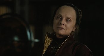 Movie still from “Queen Margot” (1994), directed by Patrice Chéreau – An older woman wearing a brown jacket and a gold necklace; Close Up shot, Over the shoulder angle