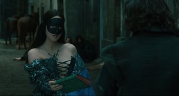 Movie still from “Queen Margot” (1994), directed by Patrice Chéreau – A woman wearing a black mask and holding a book; Medium shot, Over the shoulder angle