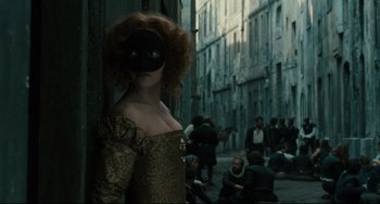 Movie still from “Queen Margot” (1994), directed by Patrice Chéreau – A woman with a black mask standing in the middle of a street; Medium shot, Over the shoulder angle