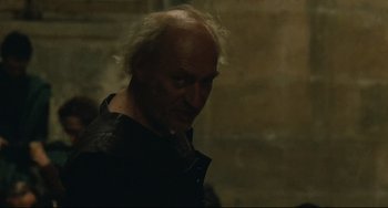 Movie still from “Queen Margot” (1994), directed by Patrice Chéreau – An old man with a white beard is standing in a dark room; Close Up shot, Low angle