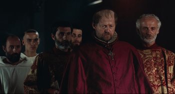 Movie still from “Queen Margot” (1994), directed by Patrice Chéreau – A group of men standing next to each other in a dark room; Medium shot, Over the shoulder angle