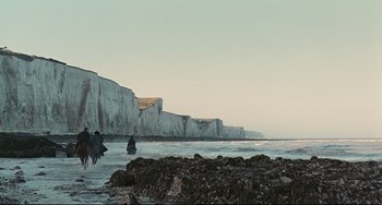 Movie still from “Queen Margot” (1994), directed by Patrice Chéreau – A couple of people standing on top of a beach next to the ocean; Extreme Wide shot, Low angle