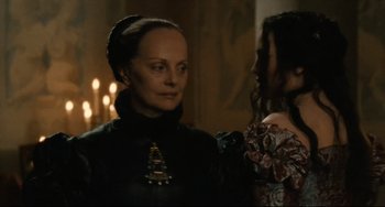 Movie still from “Queen Margot” (1994), directed by Patrice Chéreau – A woman standing next to another woman in front of candles; Close Up shot, Over the shoulder angle